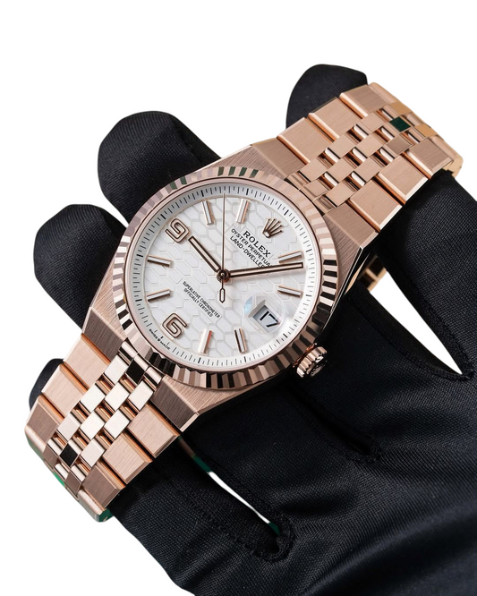 ACCHA TIME rose gold watch with a white honeycomb dial, fluted bezel, and jubilee bracelet on a gloved hand.